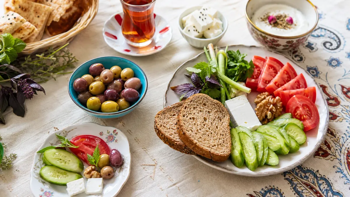 کاسه زیتون کنار نان، پنیر، خیار، گوجه و سبزی